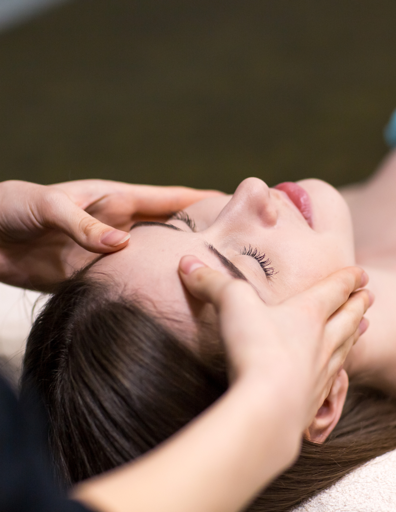 Young beautiful woman receiving head face massage in beauty spa.